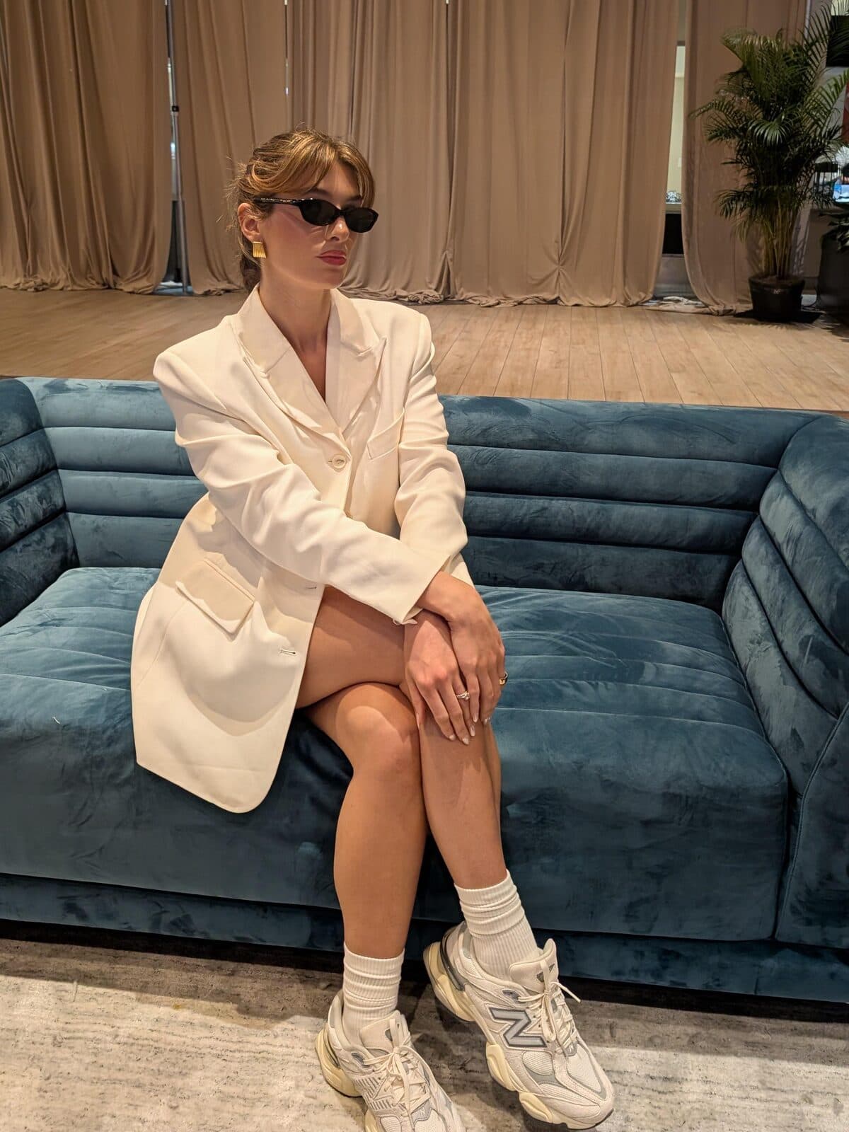 Cream blazer and sneakers on a blue velvet sofa